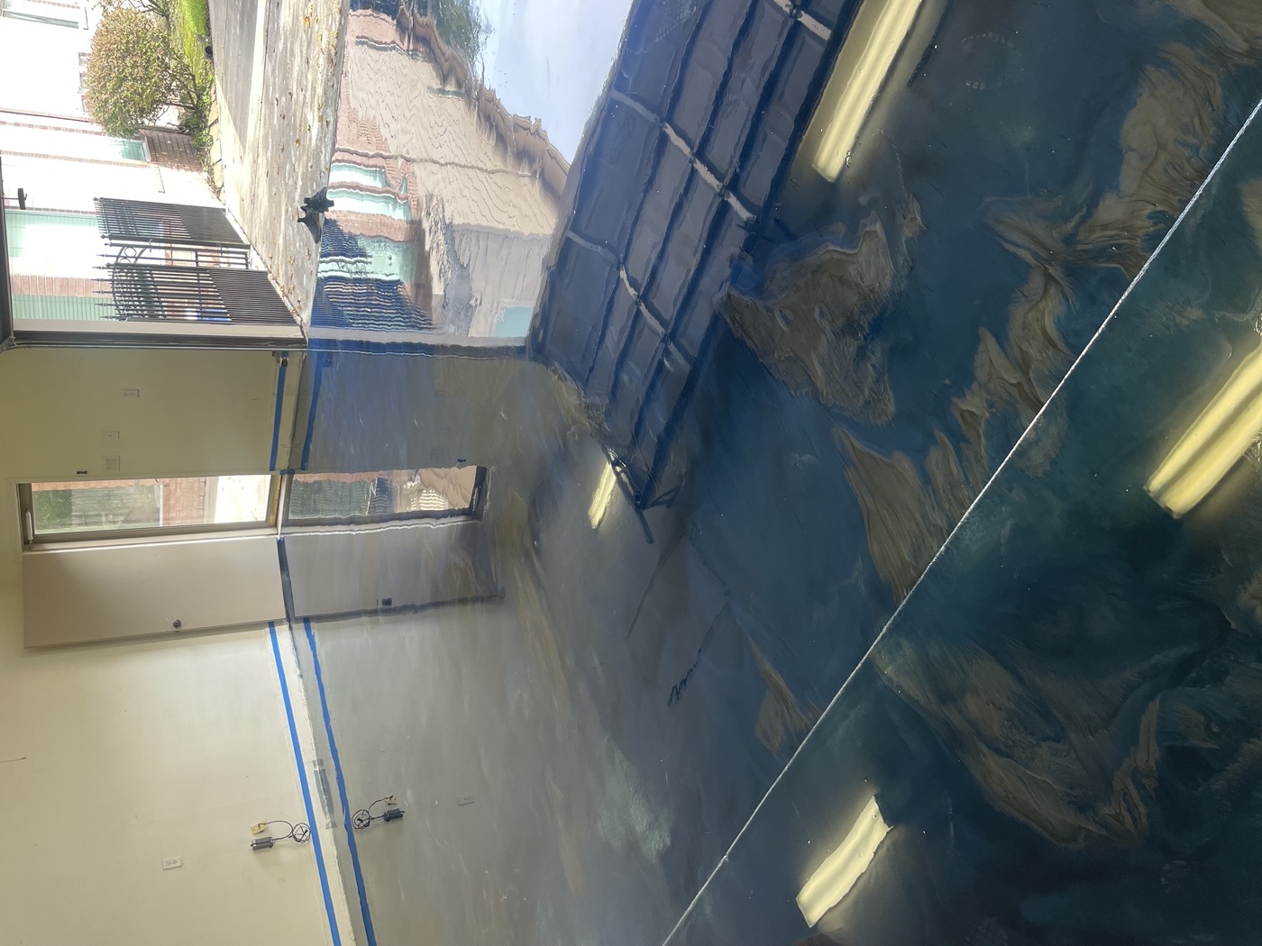 Blue and grey metallic garage floor reflecting the open doorway and surrounding architecture