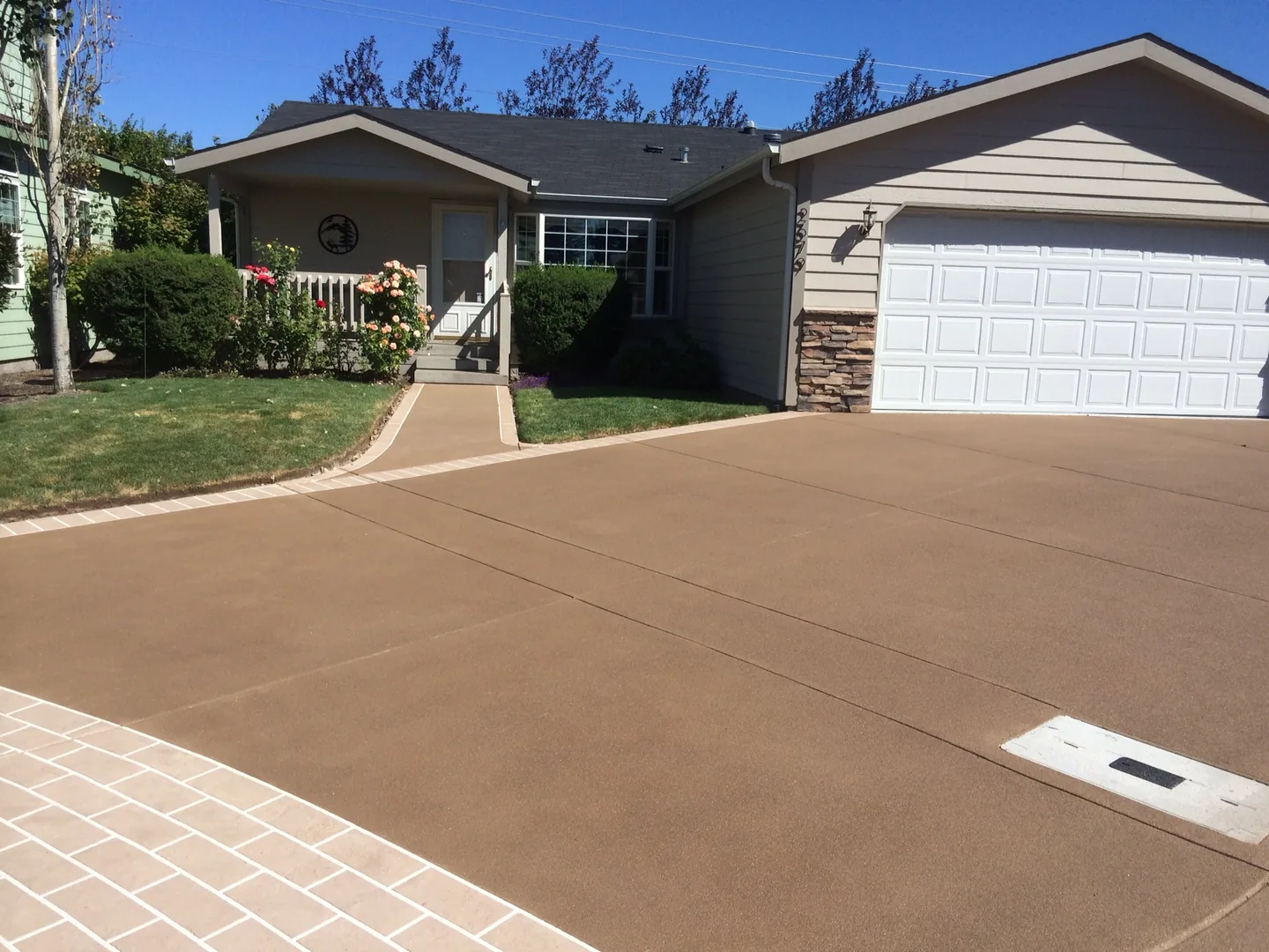 Warm brown decorative concrete driveway and matching walkway at a home